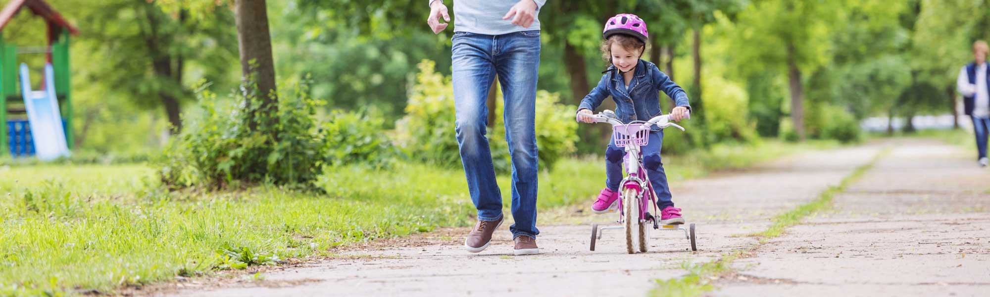 father teaching daughter to ride bike